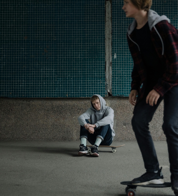 Jongere zit te kijken naar andere jongere die skate