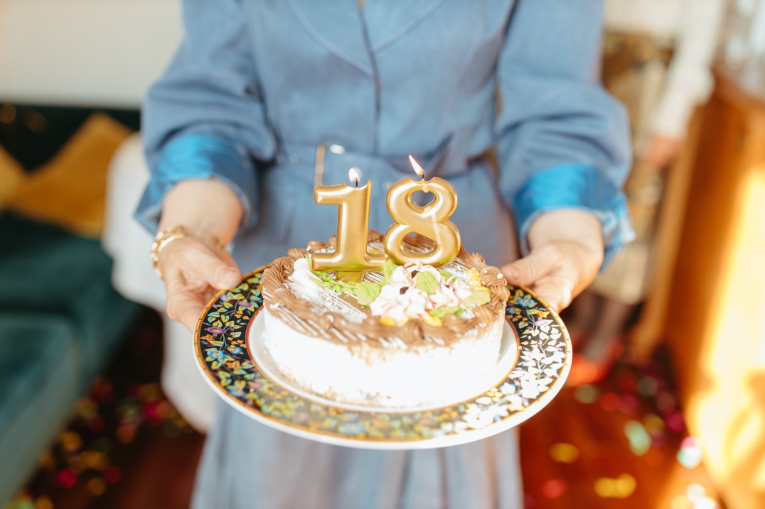 Taart met brandende kaarsen in de vorm van 18 tijdens een verjaardag.