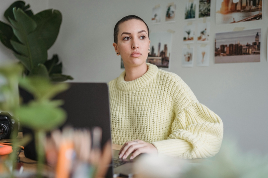 Vrouw kijkt serieus terwijl ze werkt achter haar laptop