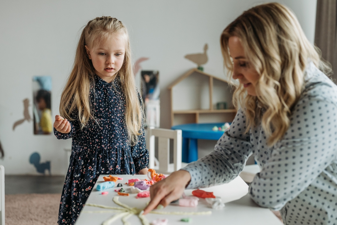Vrouw en jong meisje spelen samen met kleurrijke klei aan een tafel.